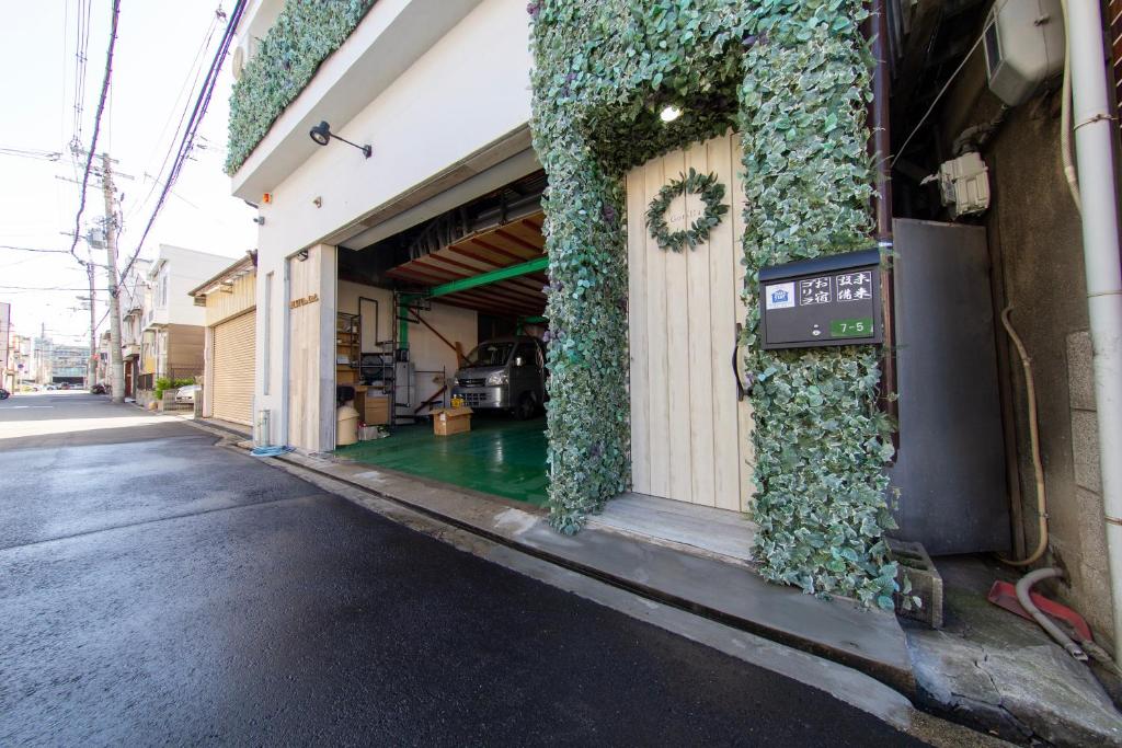 un bâtiment avec du lierre vert sur son côté dans l'établissement Guest House GORILLA!, à Osaka