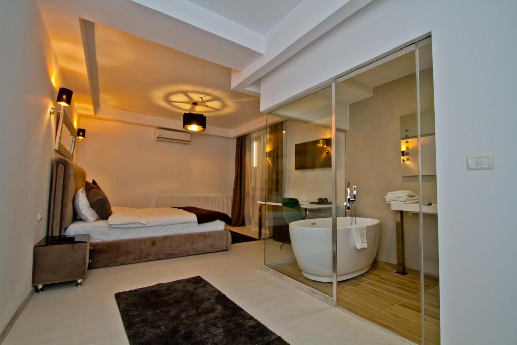 ein Bad mit einem Bett und einer Badewanne in einem Zimmer in der Unterkunft Premium Residence in Braşov