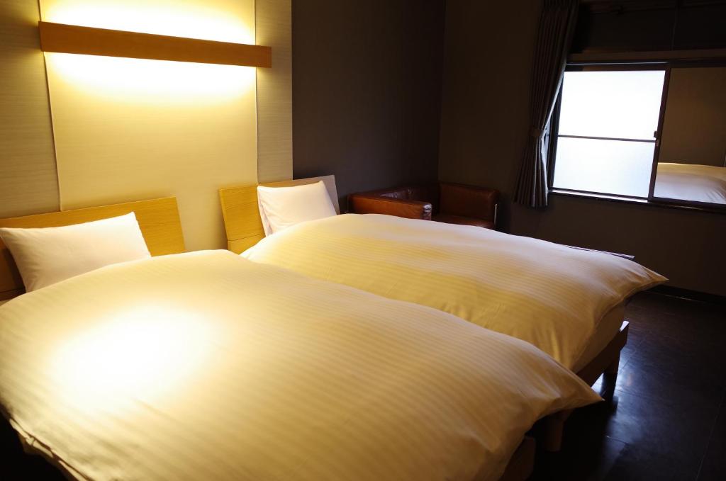 two white beds in a room with two windows at Bar 39 in Higashihiroshima