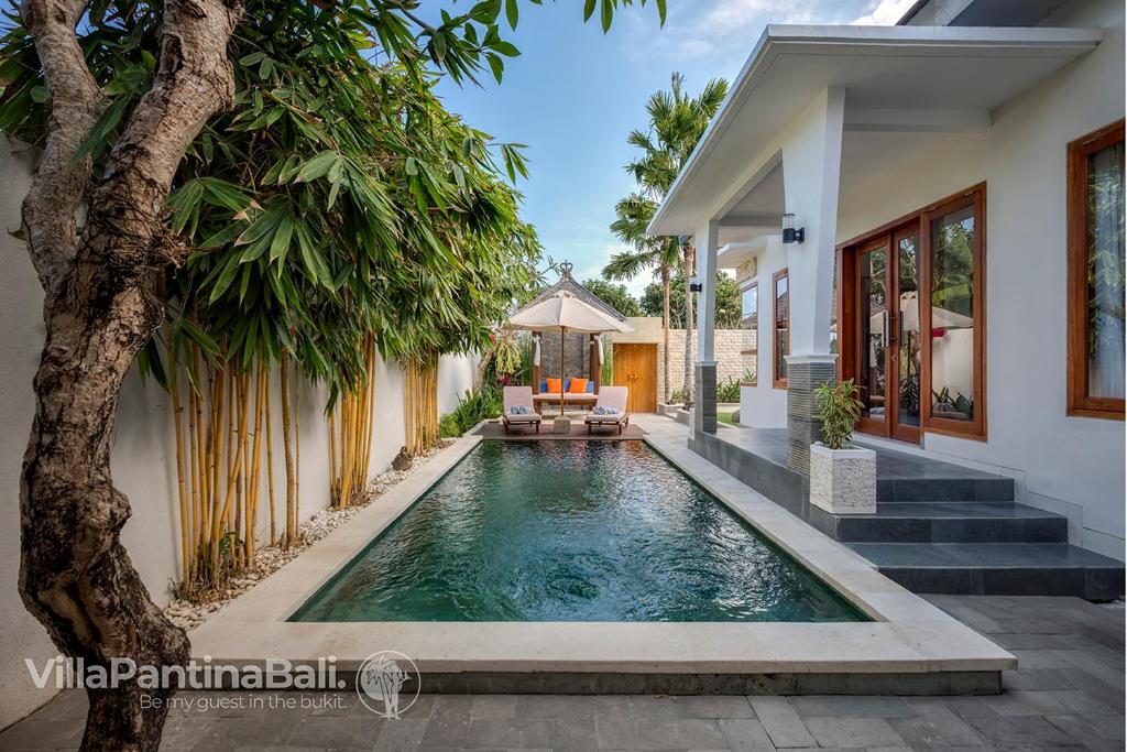a swimming pool in front of a house at Villa Pantina Bali in Uluwatu