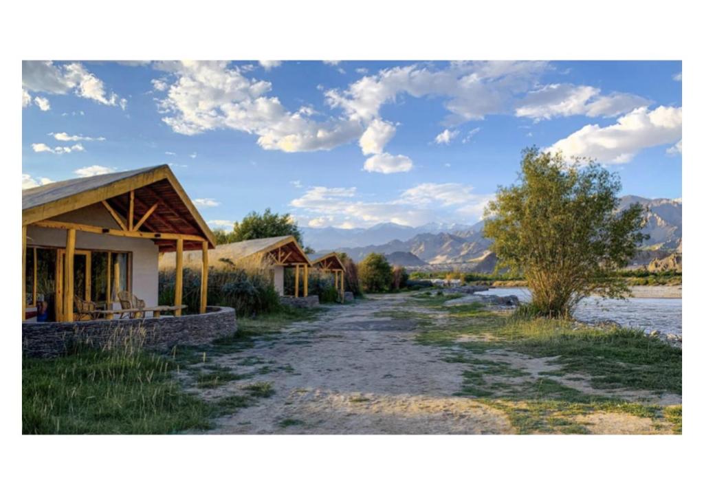 a dirt road next to a group of buildings at The Indus River Camp in Leh