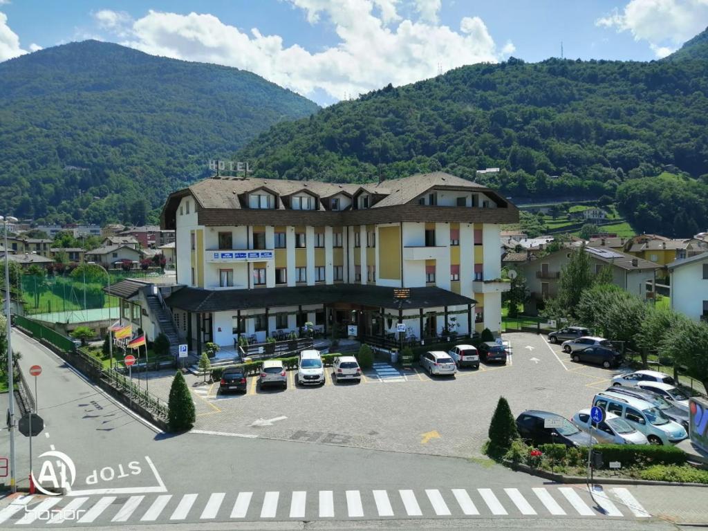 a large building with cars parked in a parking lot at Hotel Rezia Valtellina in Morbegno