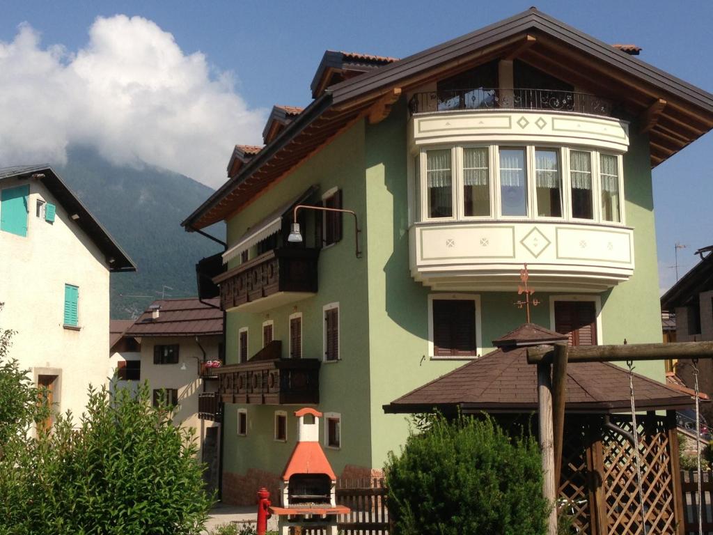 ein grünes und weißes Haus mit einem Berg im Hintergrund in der Unterkunft Villa dei Fiori in Cavedago