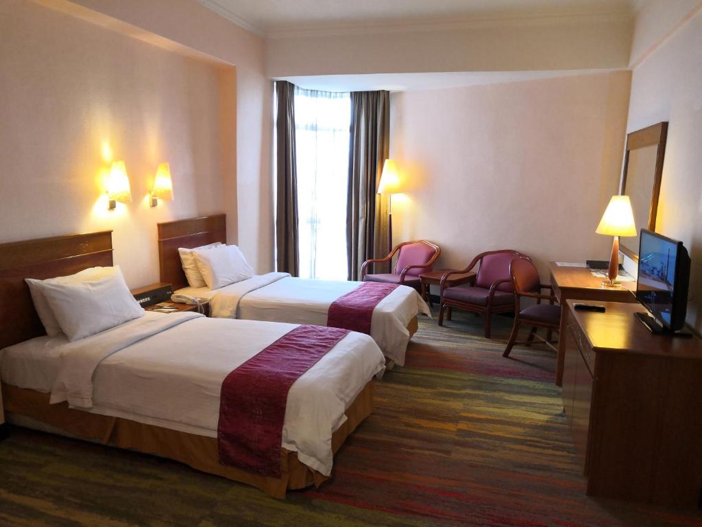 a hotel room with two beds and a television at Hotel Grand Continental Kuala Terengganu in Kuala Terengganu