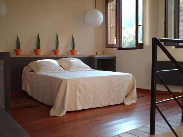 a bedroom with a bed with white sheets and a window at Casa Rural Pico Espadan in Almedíjar