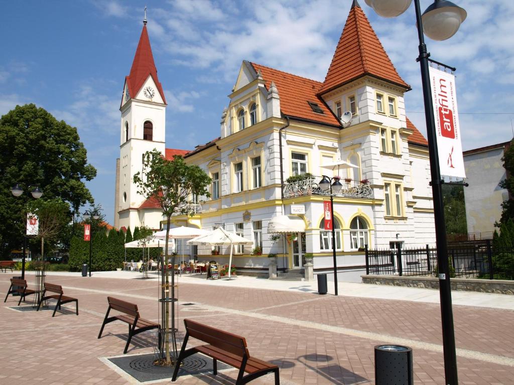 un grand bâtiment blanc avec une tour d'horloge dans l'établissement Hotel Margit, à Trenčianske Teplice