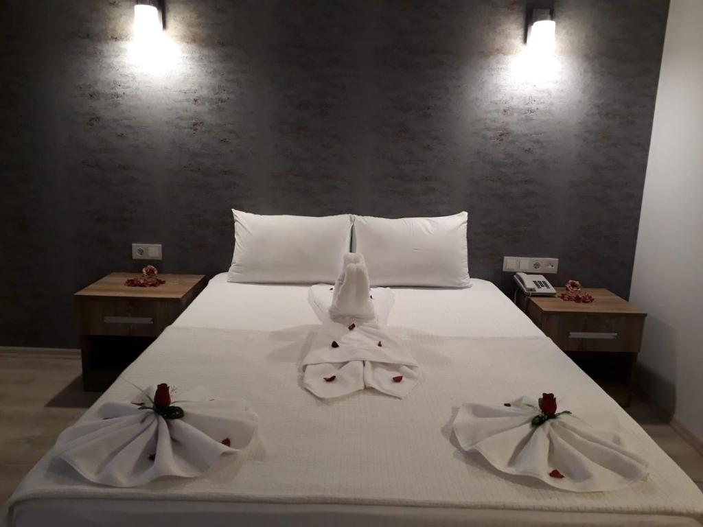 BOZKURT HOTEL في Kemaliye: سرير عليه مناشف بيضاء وطاولتين