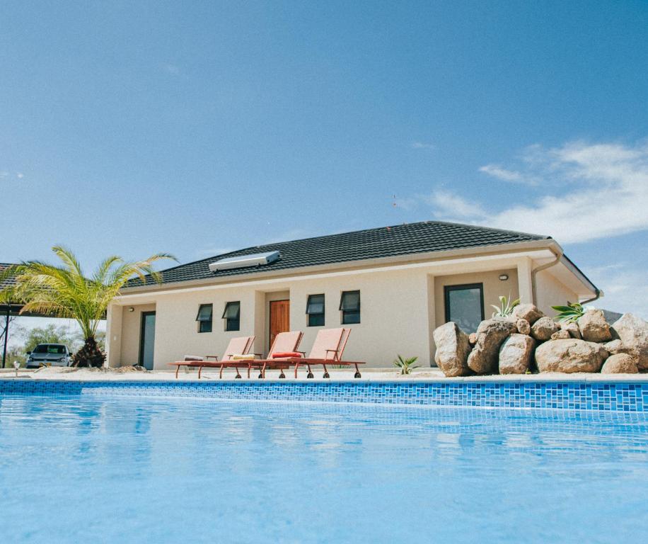 a house with a swimming pool in front of a house at Otjohotozu Guestfarm in Omaruru