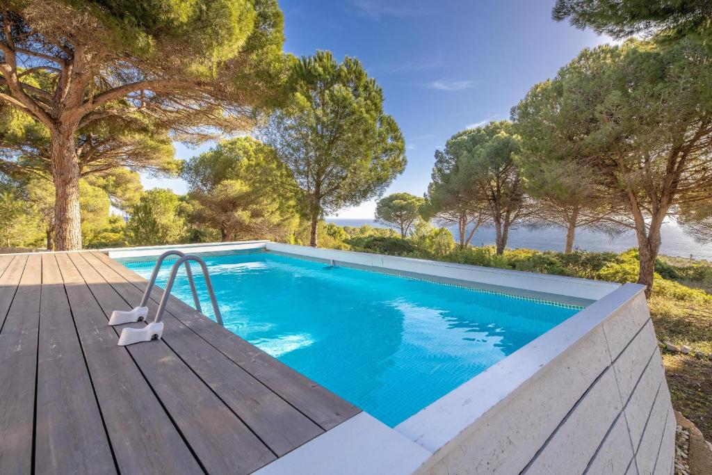 a swimming pool on a wooden deck next to the water at Villa Celestina in Corsano
