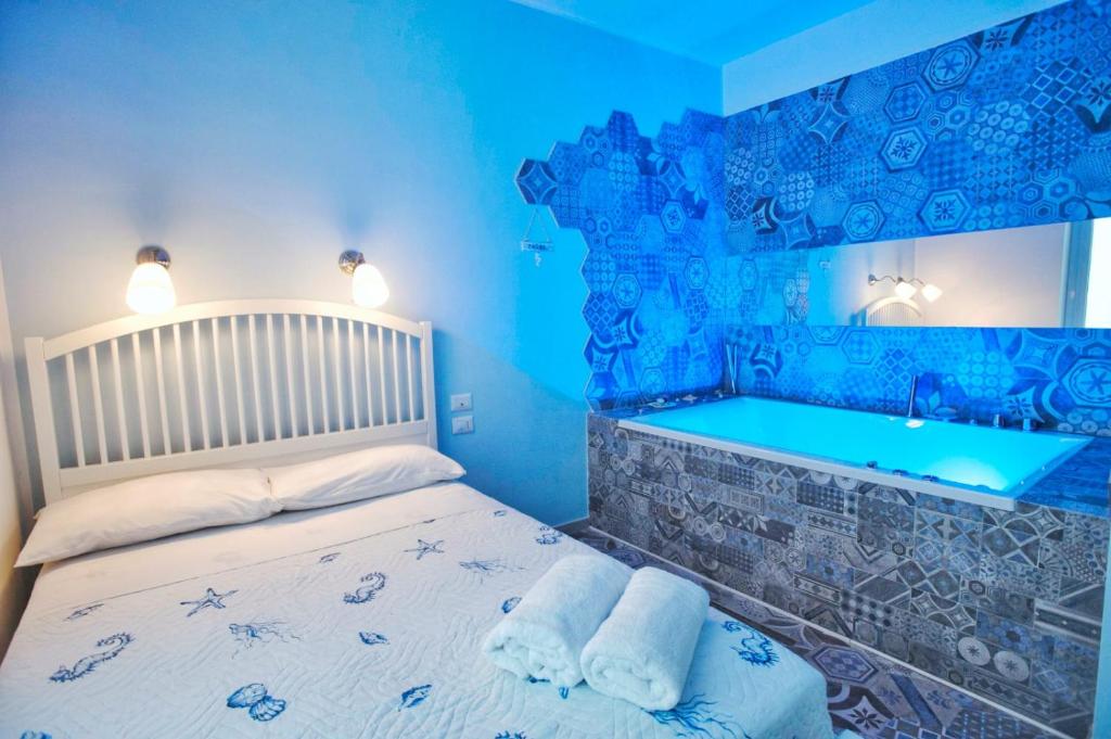 a blue bedroom with a bed and a tub at Nereidi Suites in Salerno