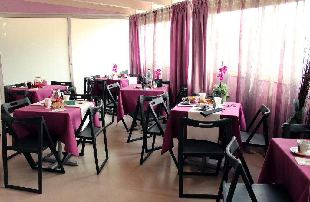 フロリーディアにあるHotel Vittorio Emanueleのピンクのテーブルと椅子、カーテンが備わるダイニングルーム