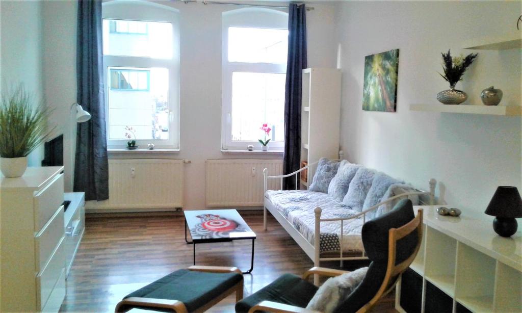 a living room with a couch and two windows at Citywohnung an der alten Maschinenfabrik - Nähe Bahnhof in Halle an der Saale