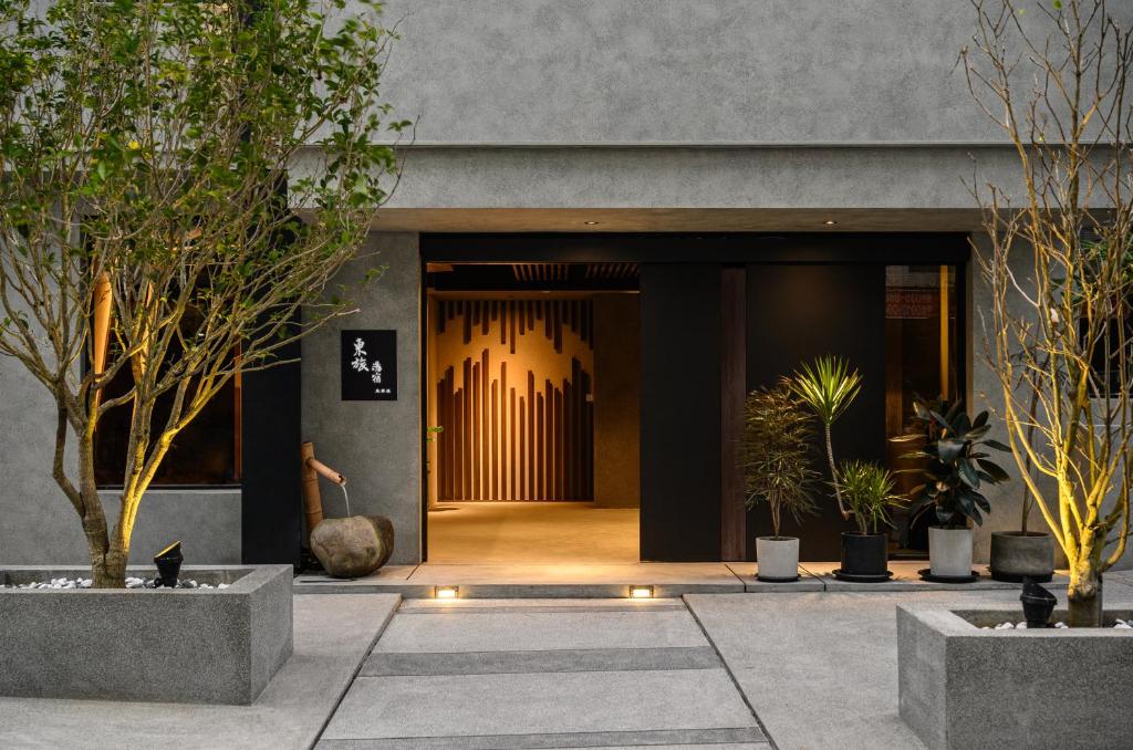 une porte d'entrée d'un bâtiment avec des plantes en pot dans l'établissement Yunoyado Onsen Hot Spring Hotel Deyang, à Jiaoxi