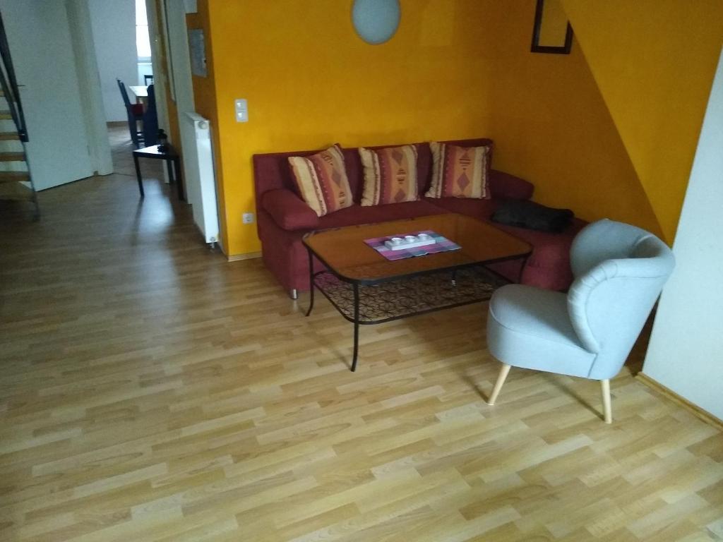 Maisonettewohnung auf 2 Etagen mit zwei Balkonen في بارث: غرفة معيشة مع أريكة وطاولة وكرسي