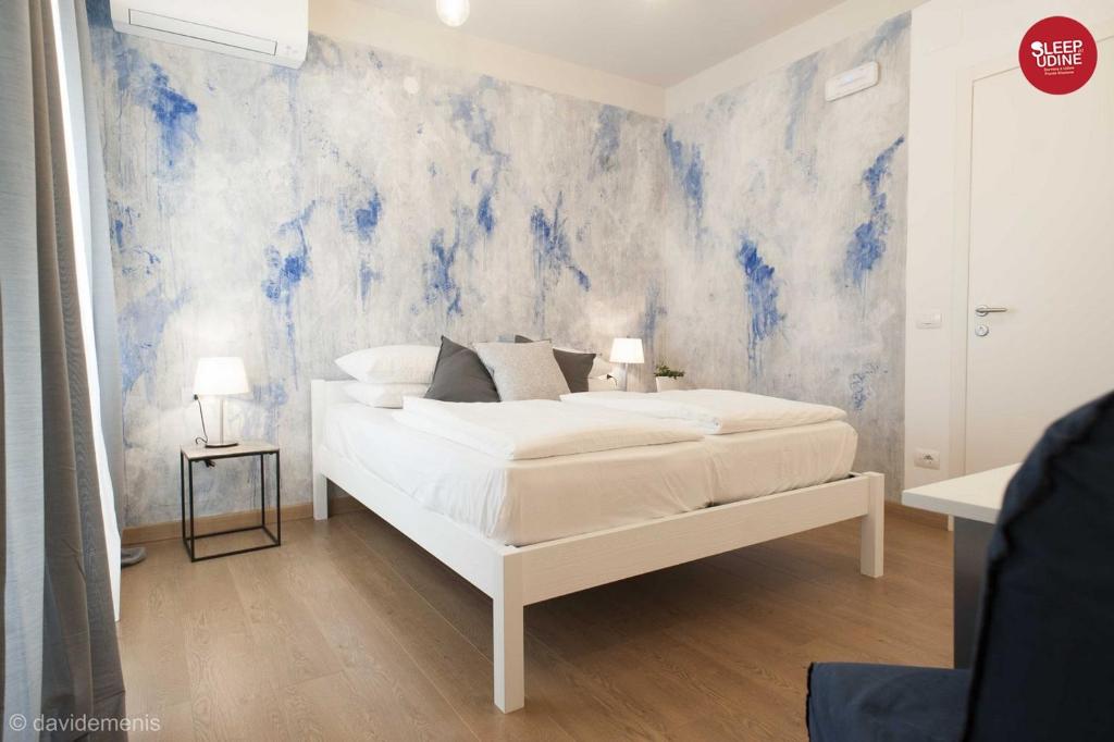 Sleep In Udine في أوديني: غرفة نوم بسرير ابيض وجدار ازرق