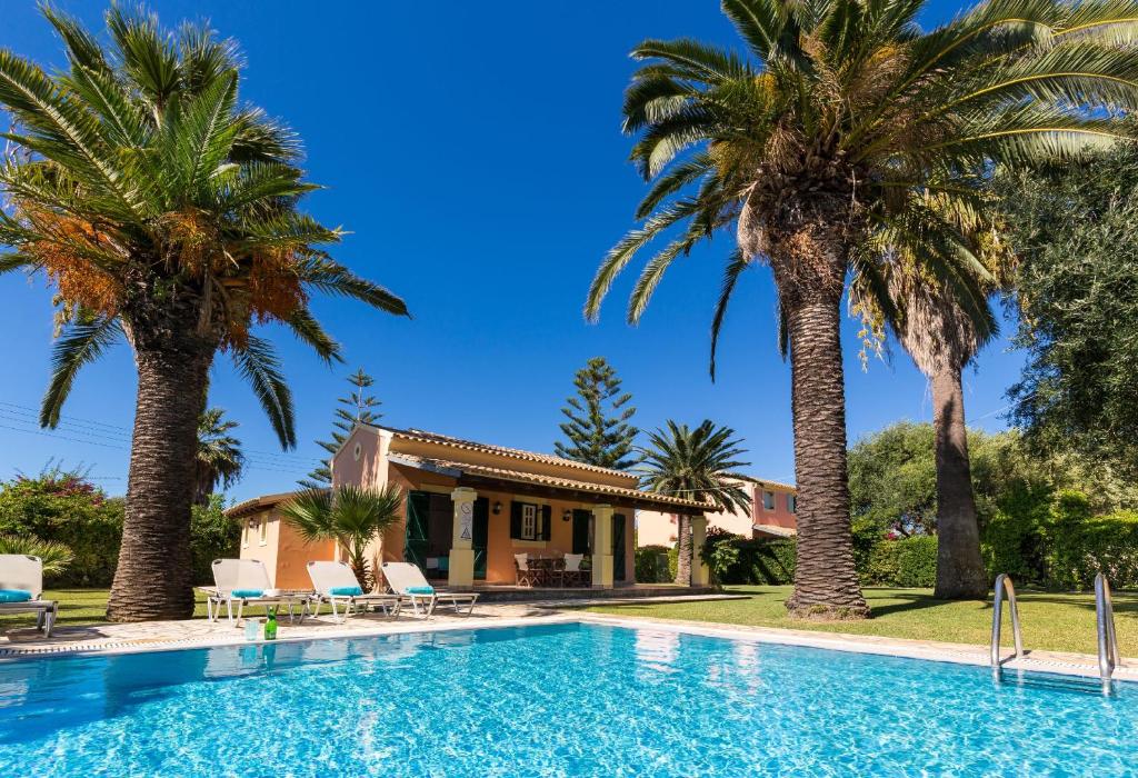 a villa with a swimming pool and palm trees at Villa Angelos in Acharavi