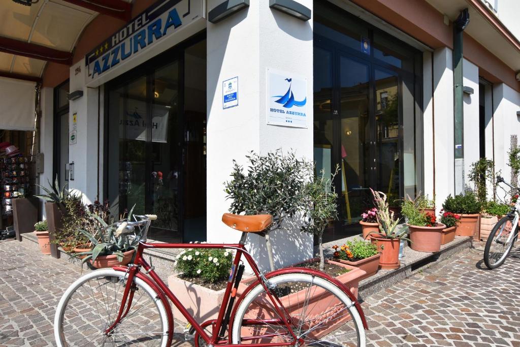 czerwony rower zaparkowany przed sklepem w obiekcie Hotel Azzurra w Rimini