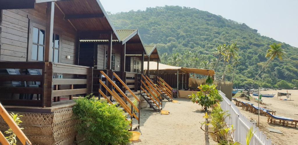 a building on the beach with a mountain in the background at Summer Sky Beach Resort in Agonda