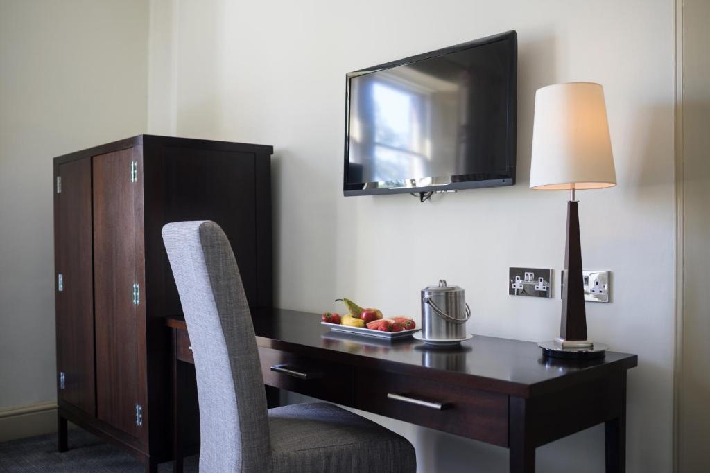 a desk in a hotel room with a television and a chair at Nether Abbey Hotel in North Berwick