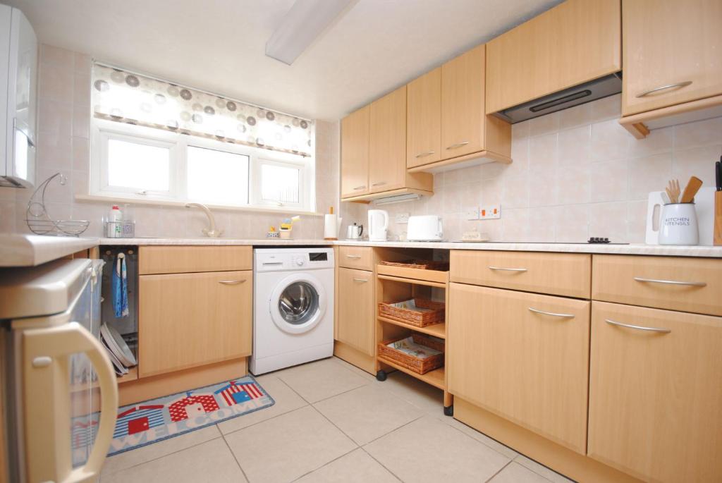 a kitchen with wooden cabinets and a washing machine at Cullimore, West Wittering in West Wittering