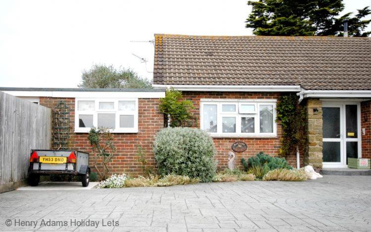 a brick house with a car parked in front of it at Cullimore, West Wittering in West Wittering