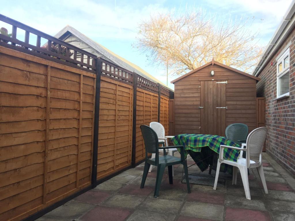 a patio with a table and chairs and a fence at Cullimore, West Wittering in West Wittering