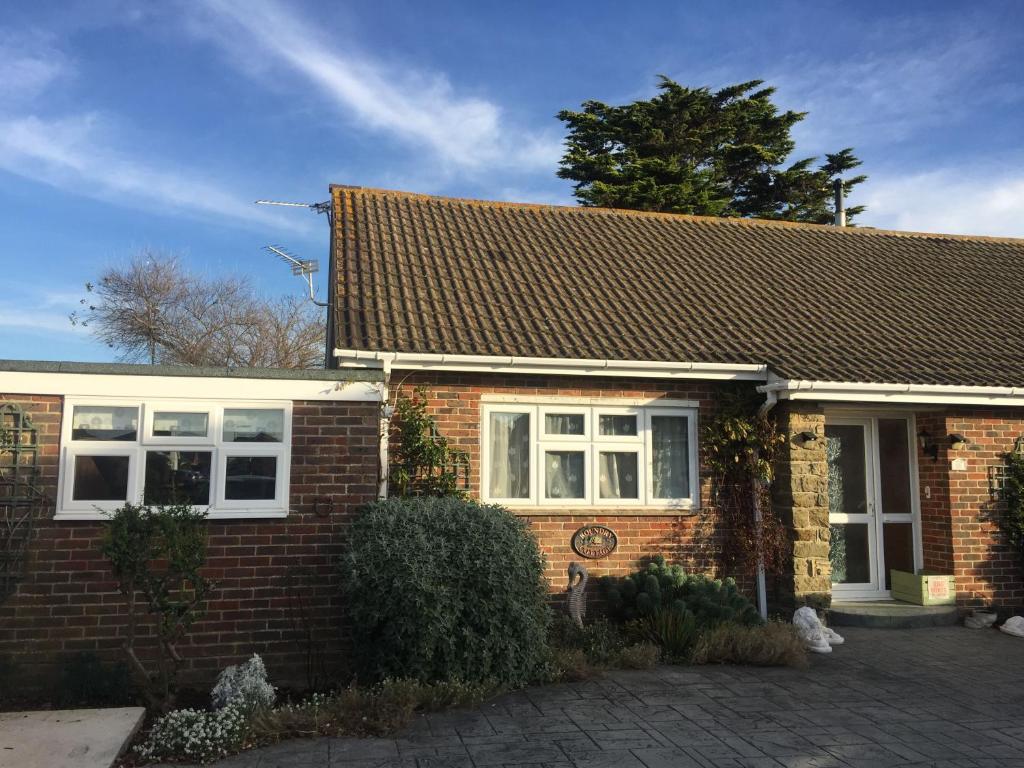 a brick house with white windows and a roof at Cullimore, West Wittering in West Wittering