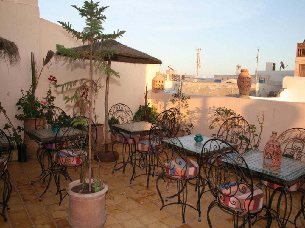 an outdoor patio with tables and chairs and plants at Riad Etoile D'essaouira in Essaouira