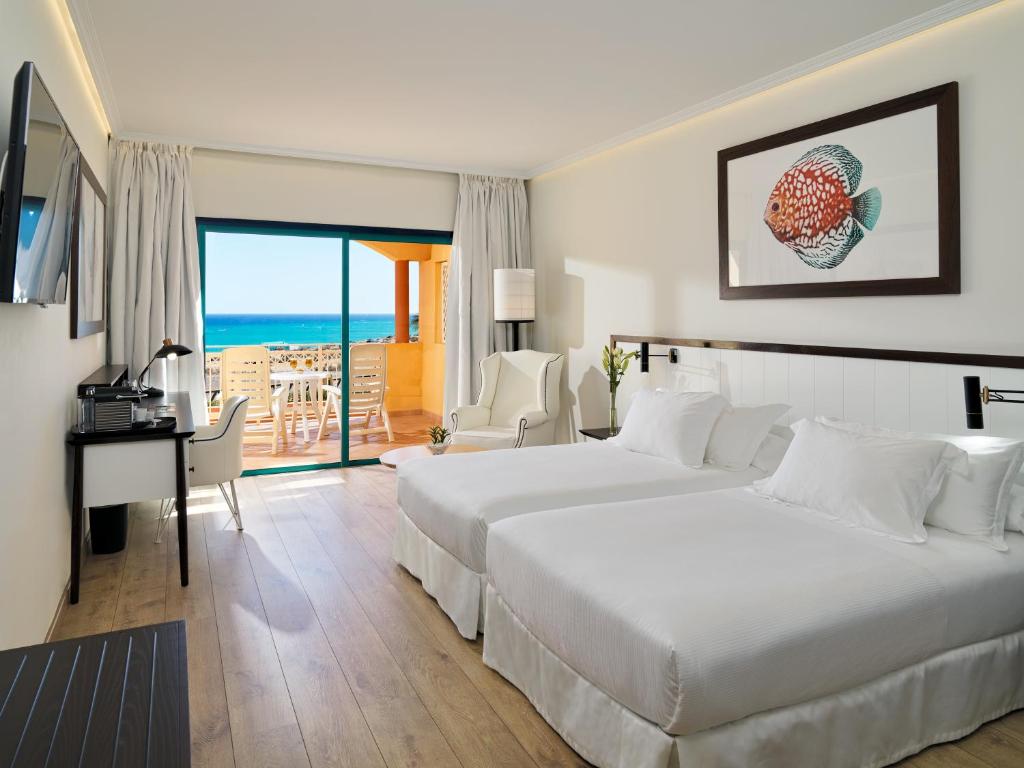 a hotel room with two beds and a desk with a view at H10 Playa Esmeralda - Adults Only in Costa Calma