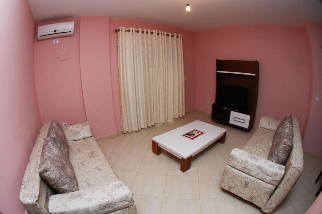 薩蘭達的住宿－Gelsi Apartments，客厅配有两把椅子、一张桌子和一台电视