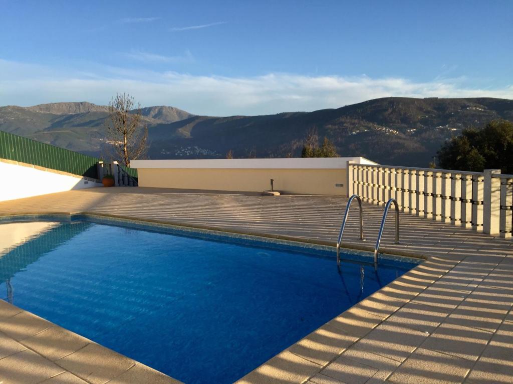 a swimming pool with a wooden deck and mountains in the background at Casa da Quinta in Oliveira do Hospital