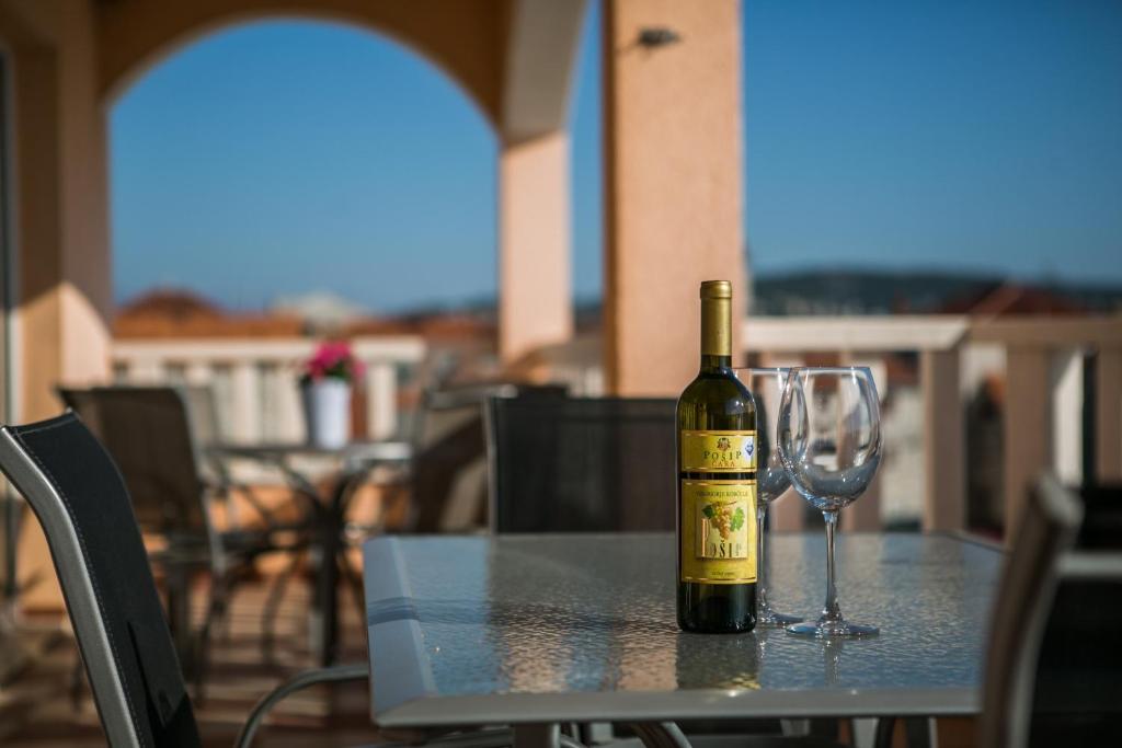 a bottle of wine sitting on a table with a wine glass at Kaja - right next to the beach in Trogir