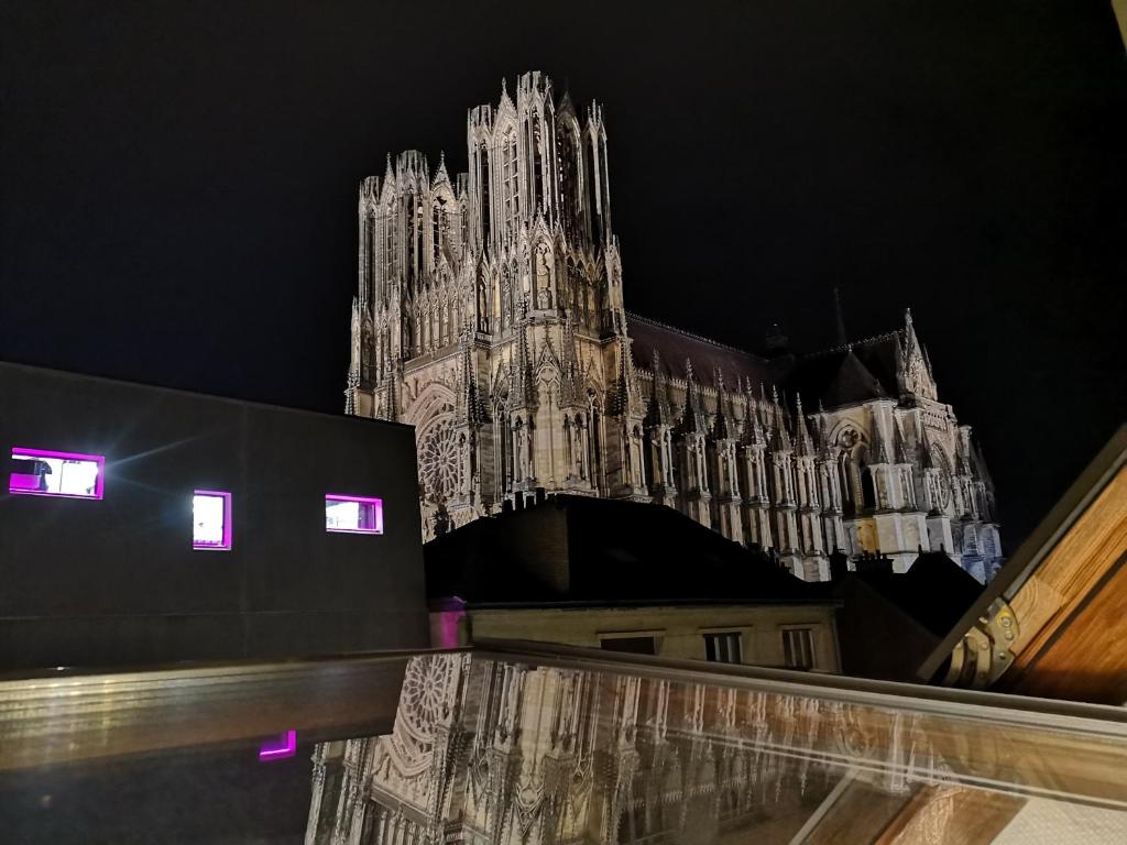 un gran edificio con una torre de reloj por la noche en Logement Cosy rénové au pied de la Cathédrale avec climatisation, en Reims