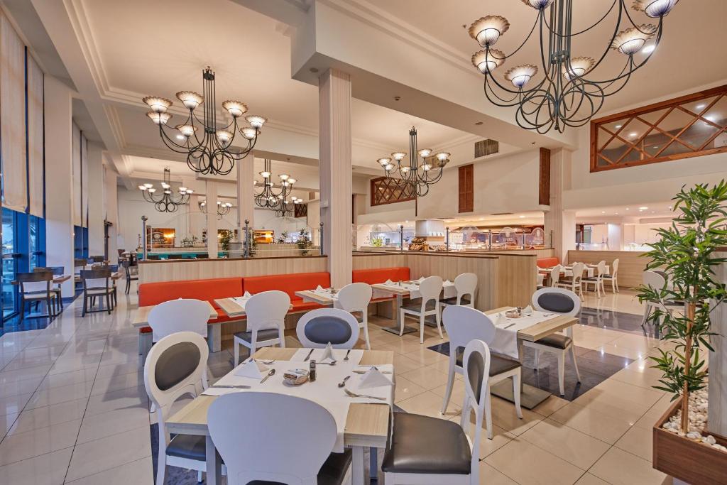 a restaurant with white tables and chairs and a bar at Sandos Papagayo in Playa Blanca