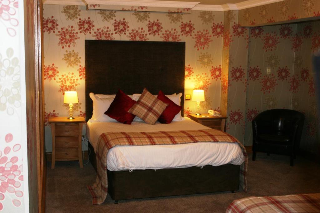 a bedroom with a large bed with red pillows at Royal Court Hotel in Portrush