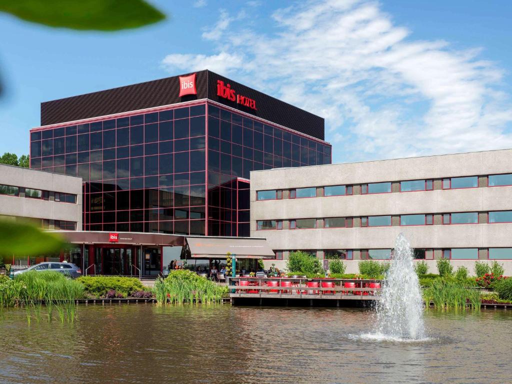 a building with a fountain in the water in front of it at Ibis Schiphol Amsterdam Airport in Badhoevedorp