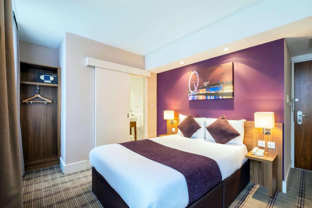 a hotel room with a large bed and purple walls at KC Inn Hotel in London