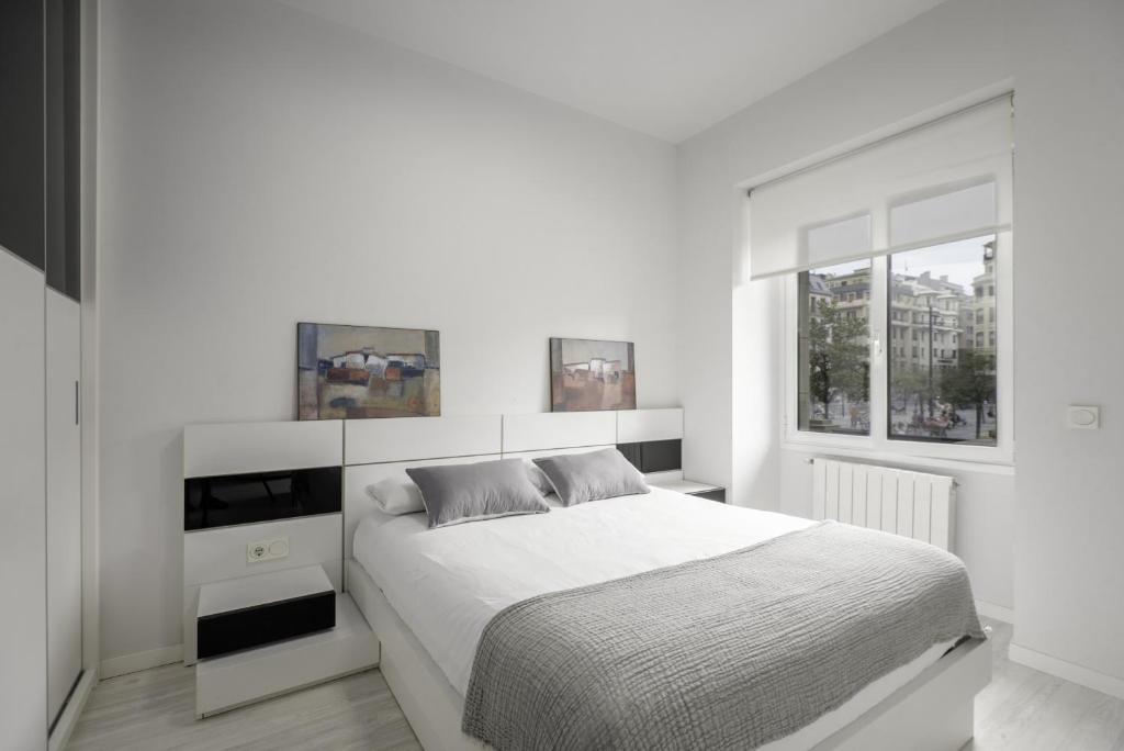 Habitación blanca con cama y ventana en Picasso - Local Rentss en San Sebastián
