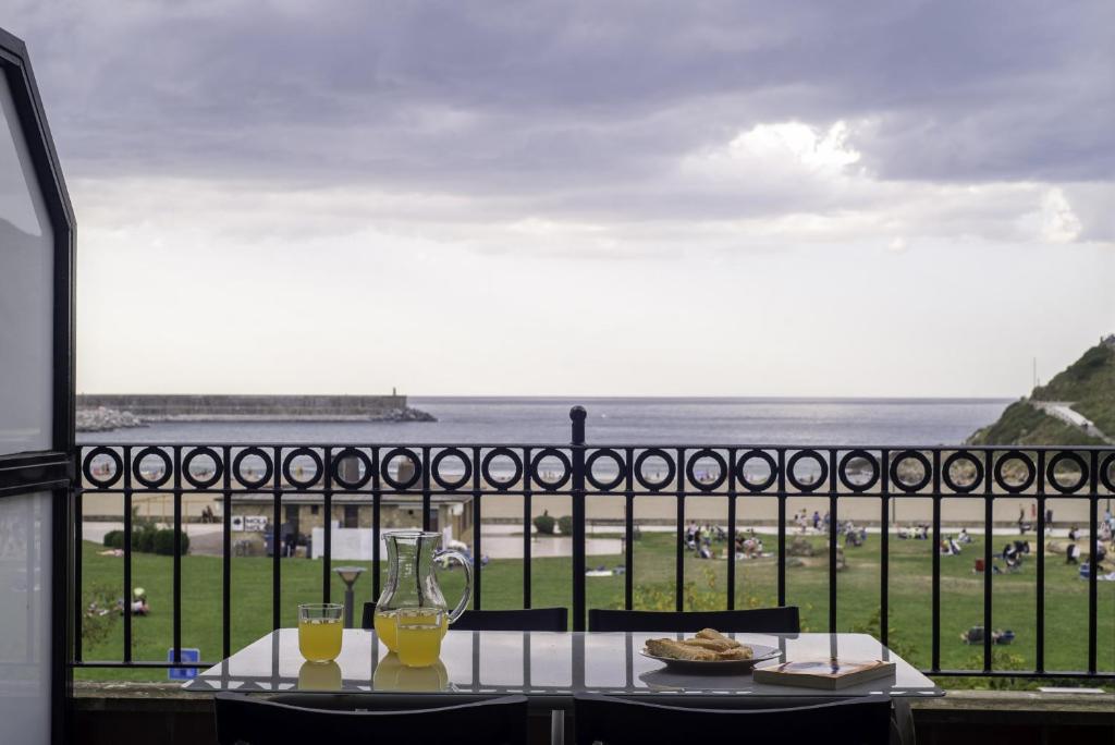 a table with two glasses and a view of the ocean at Balea 2 - Local Rentss in Orio