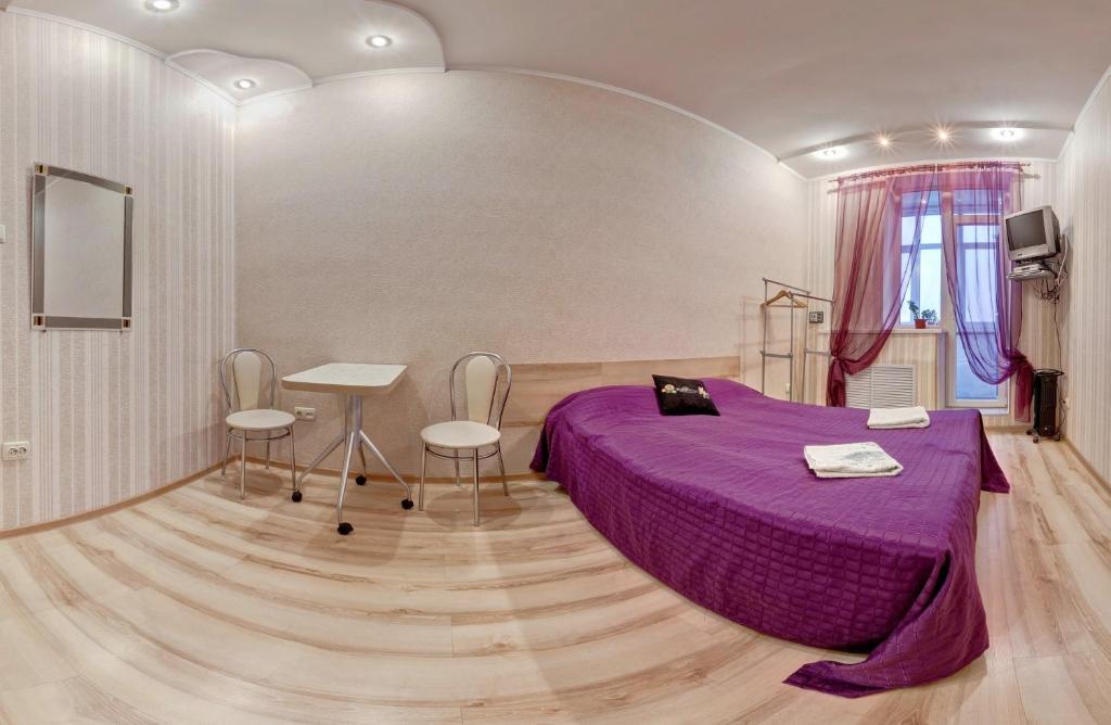 - une chambre avec un lit violet, une table et des chaises dans l'établissement Kharkov CITIZEN, à Kharkov
