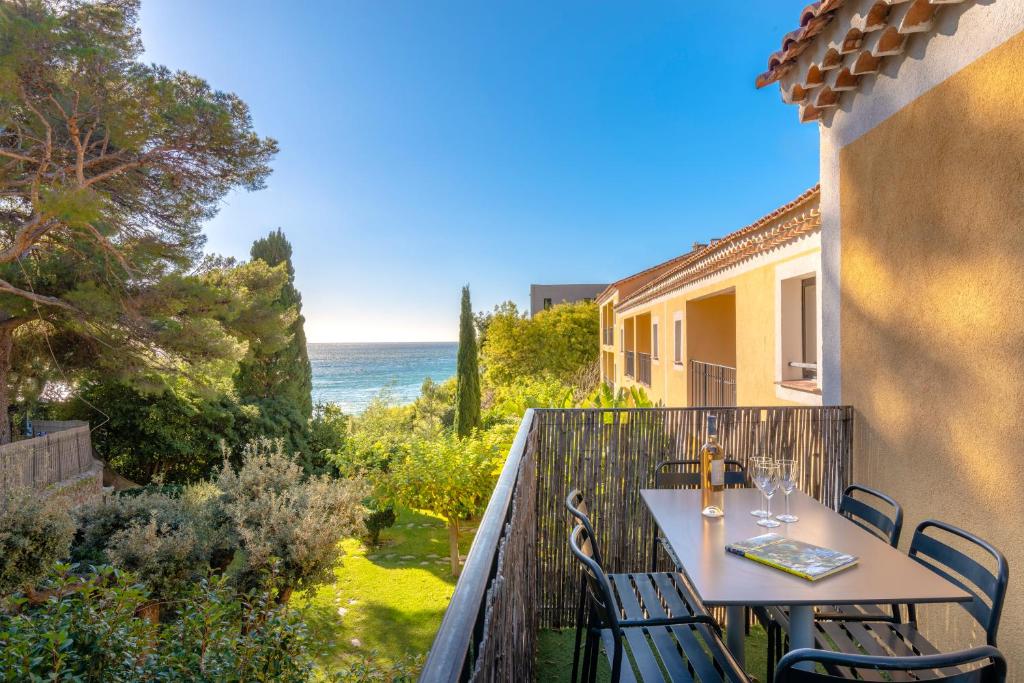 a balcony with a table and chairs and the ocean at La Résidence du Bailli in Rayol-Canadel-sur-Mer