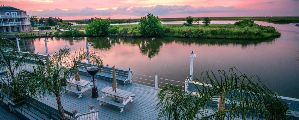 a dock with two benches on a body of water at Waterfront Villa with Deck - 23 Mi to French Quarter! in Venetian Isles