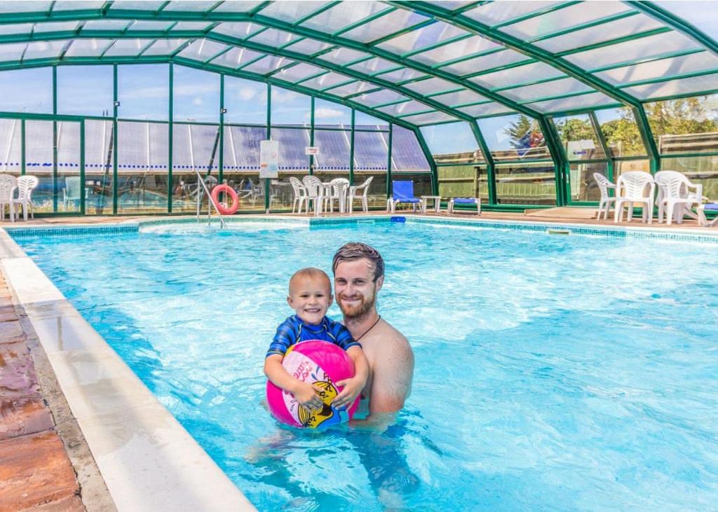 een man die een baby vasthoudt in een zwembad bij Stunning Home In Axminster W- in Axminster
