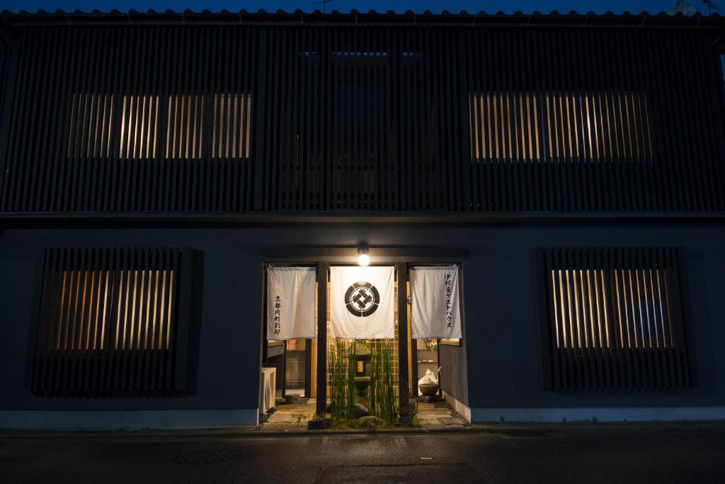 un edificio con un cartel en la puerta por la noche en Nakamuraya Kyoto Enmachi Momiji en Kioto