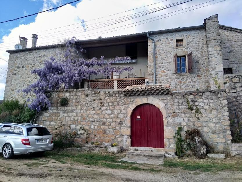 une maison en pierre avec une porte rouge et une voiture garée devant dans l'établissement mas cevenol, à Rosières
