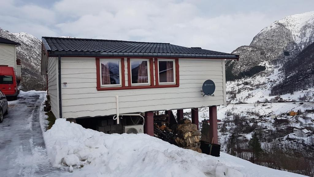 a small house in the snow next to a mountain at Leilighet 2240 in Haugsvær