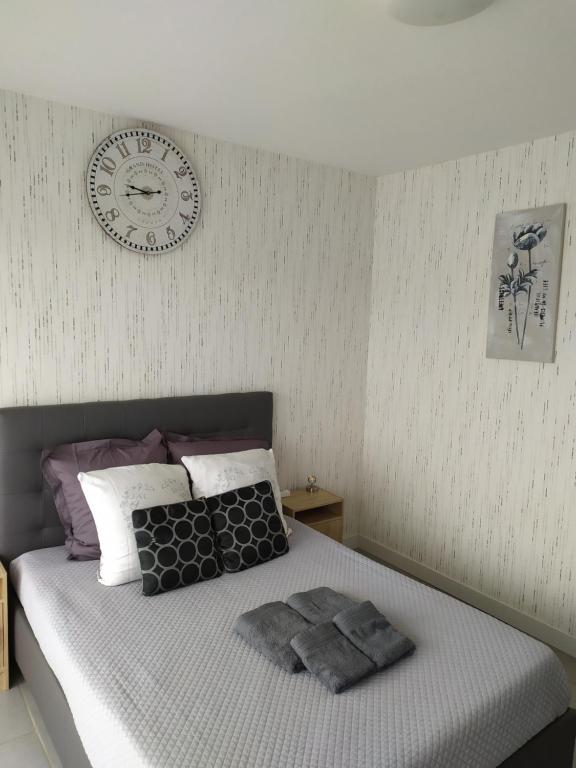 Zen attitude Appt 127 في سونس: غرفة نوم مع سرير مع ساعة على الحائط