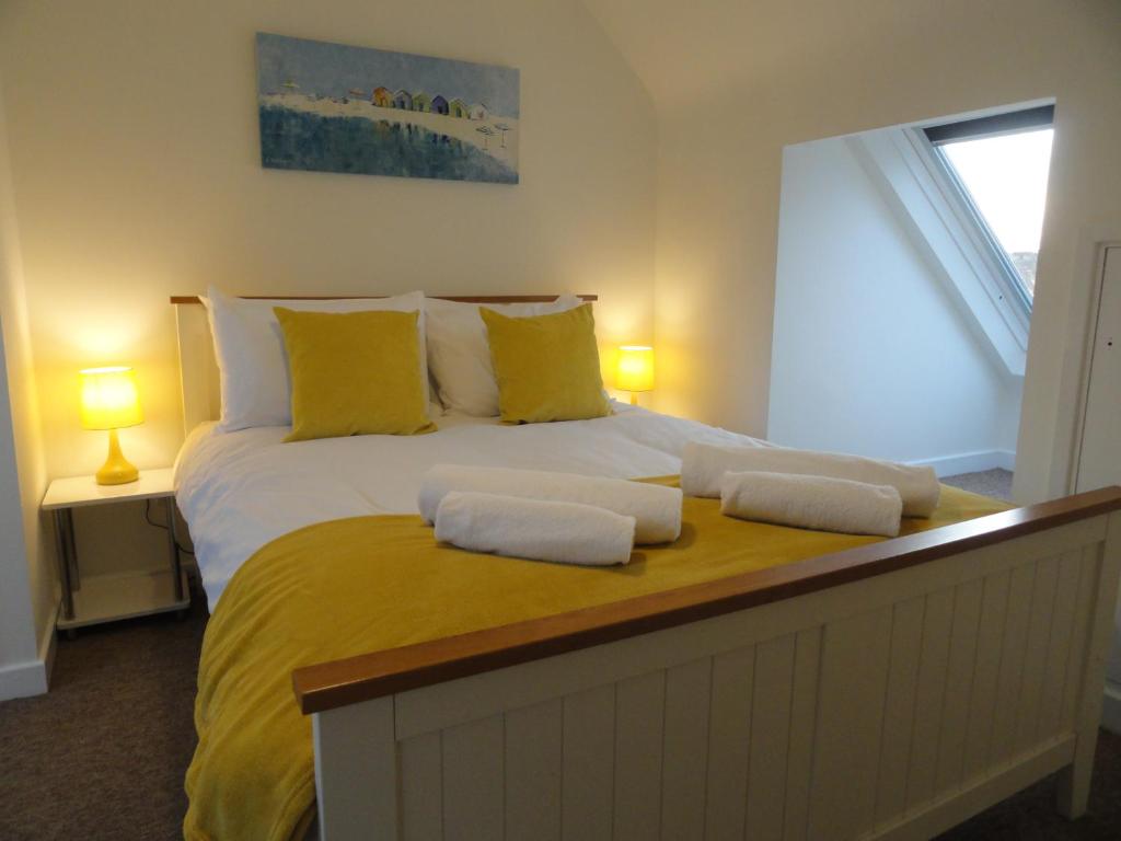 Luckwell Too by Cliftonvalley Apartments في بريستول: غرفة نوم بسرير كبير مع مخدات صفراء