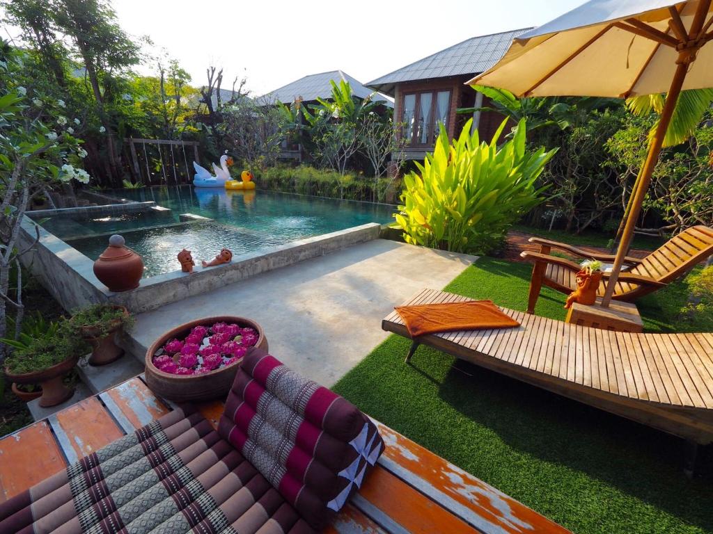 um quintal com uma piscina com um sofá e cadeiras em BaanSuk Sukhothai Resort em Sukhothai