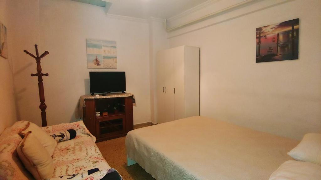 małą sypialnię z łóżkiem i telewizorem w obiekcie Yiannis Kalimarmaro Studio,Athens Center w Atenach
